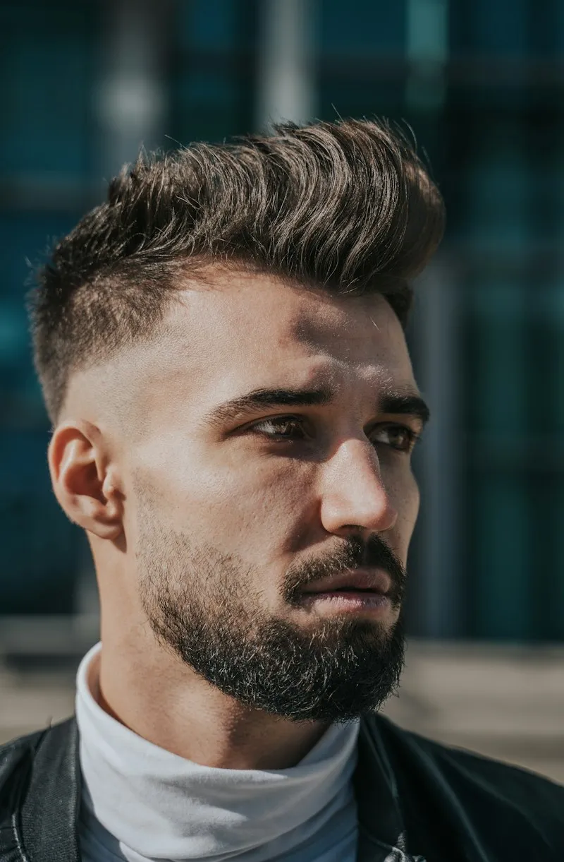 Homme portant une coupe classique coiffée vers l’arrière et une barbe taillée
