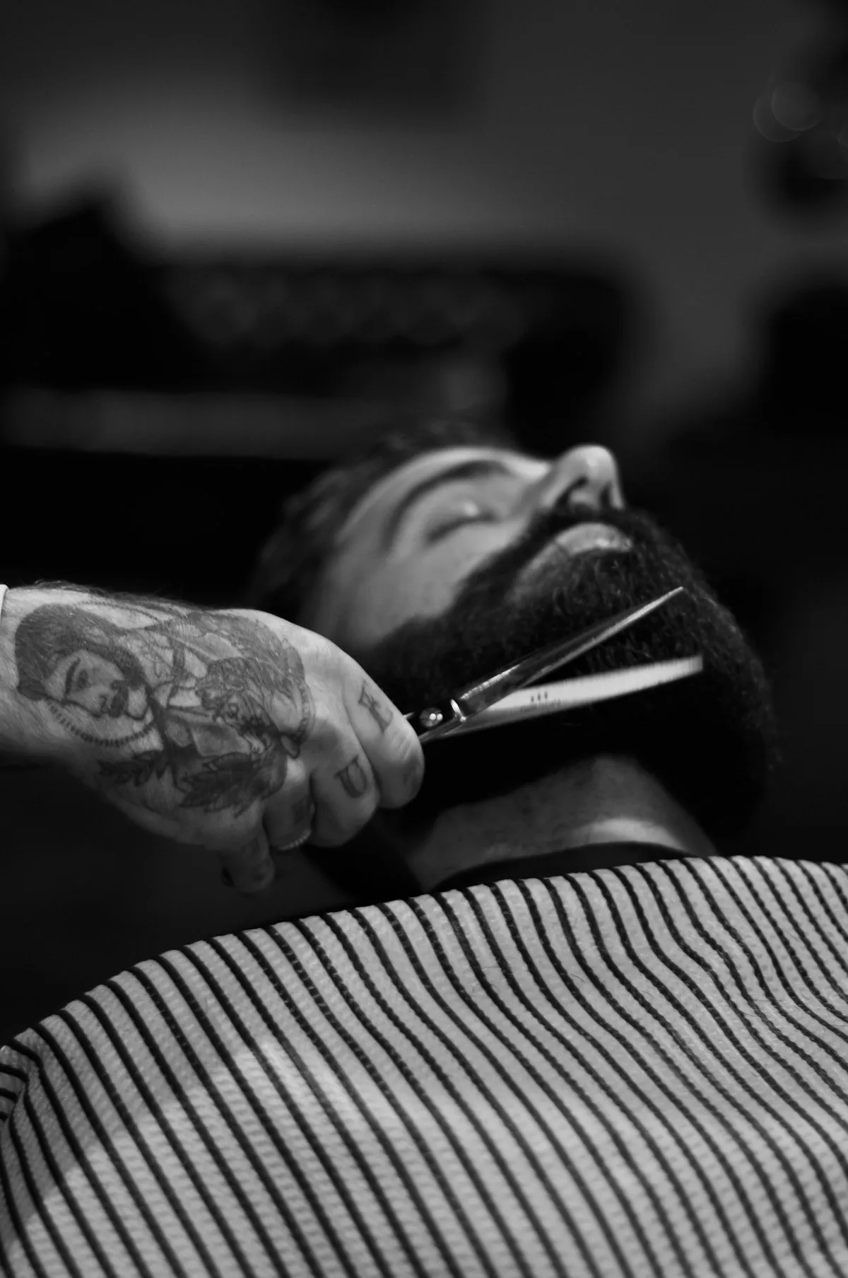 Barbier taillant une barbe aux ciseaux, en noir et blanc