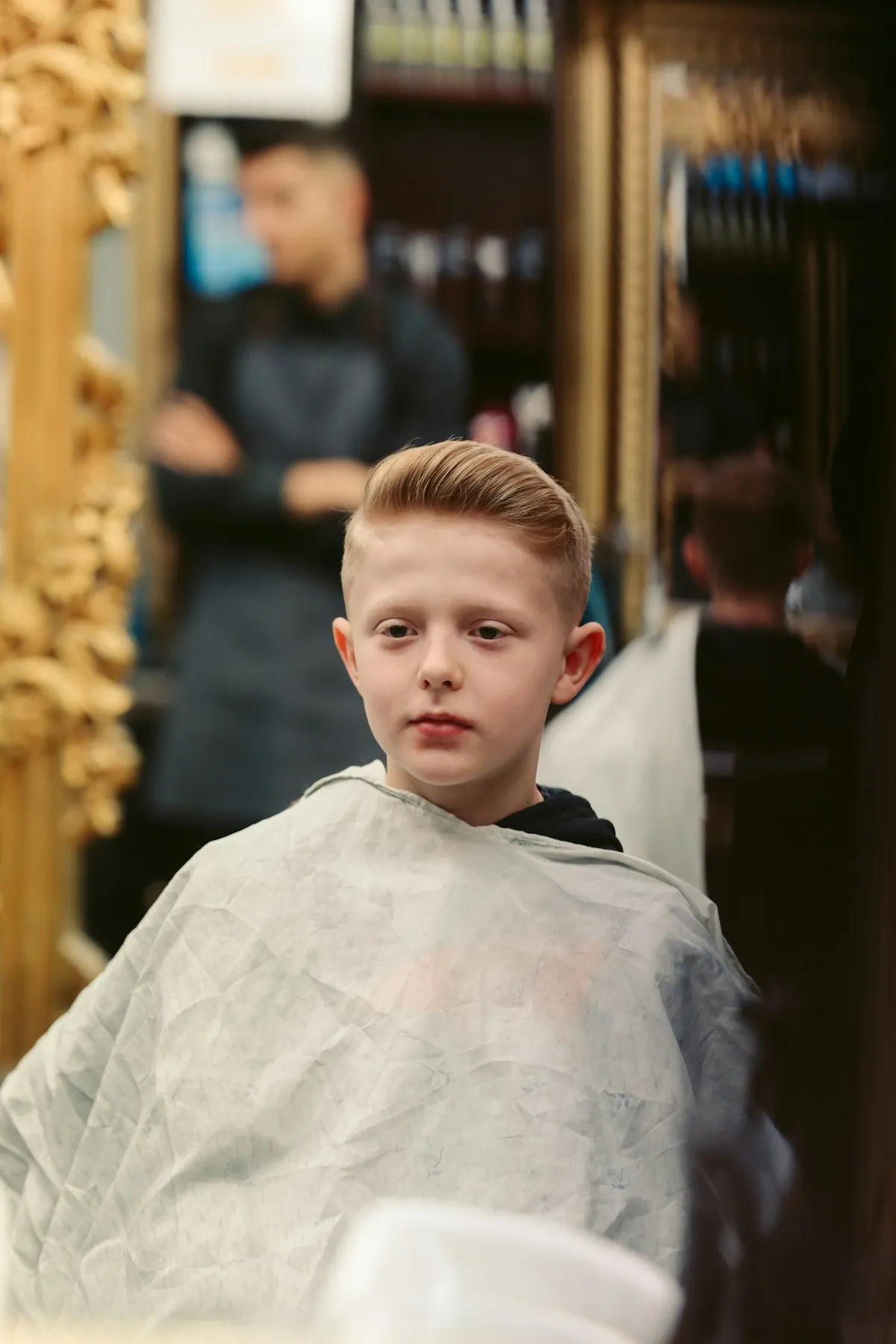 Jeune garçon assis dans un fauteuil de barbier pendant sa coupe