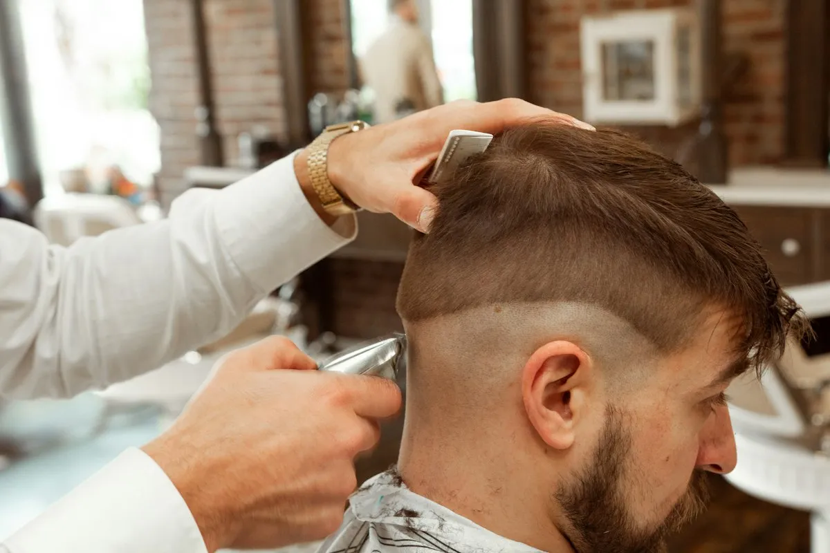Barbier travaillant un dégradé sur les côtés de la tête d’un client